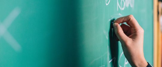 person writing on a chalkboard