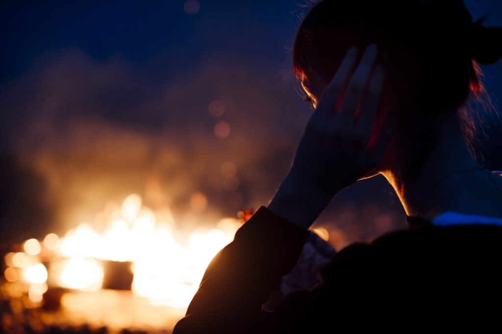 woman standing with fire in the background