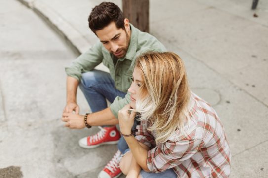 man and woman talking on a curb