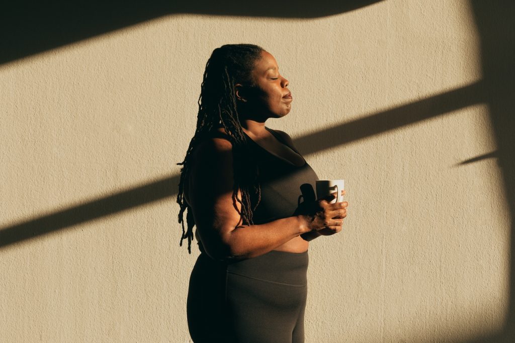 Woman holding coffee in the sun