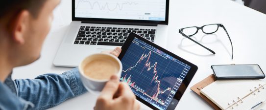 Person looking at a stock portfolio while drinking coffee