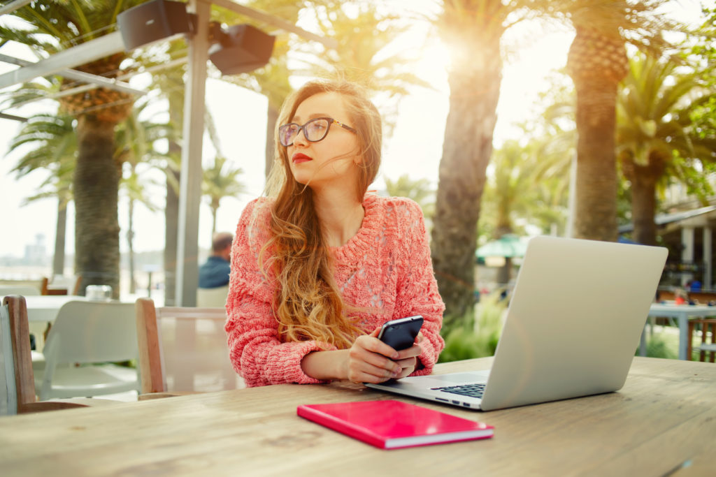 woman working at a table with palm trees in the background