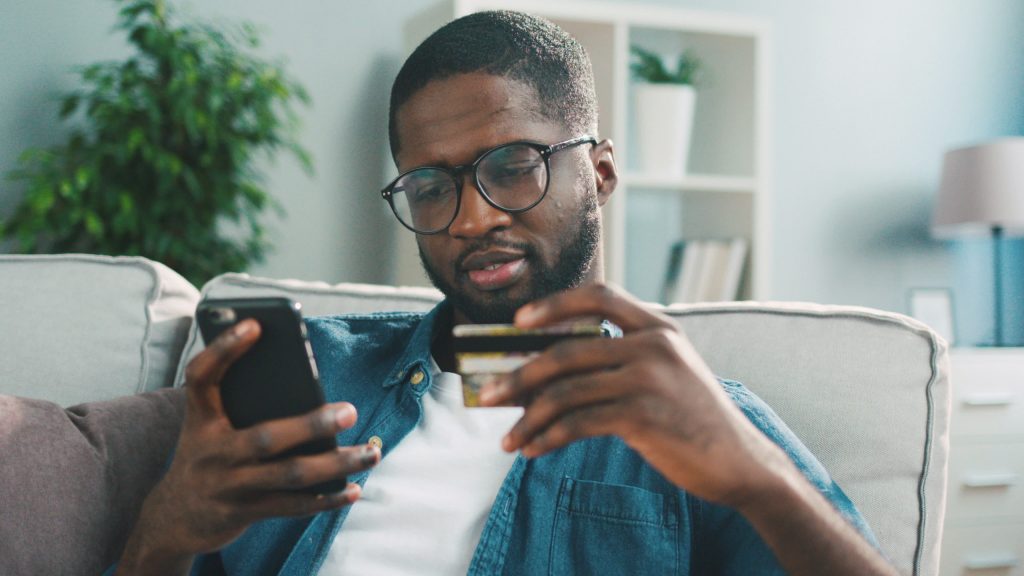 man looking at a credit card and his phone