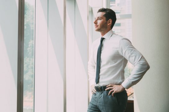man in business attire looking out a window
