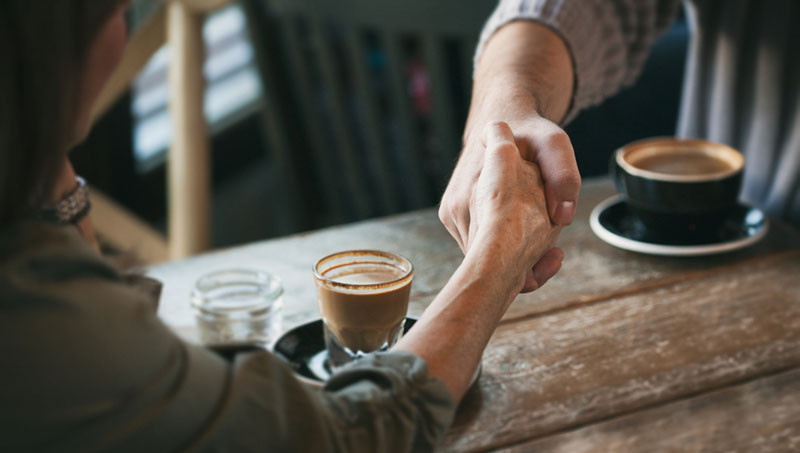 People Shaking Hands Over Coffee